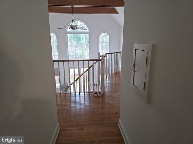 corridor featuring vaulted ceiling with beams, an upstairs landing, dark wood-style flooring, and baseboards