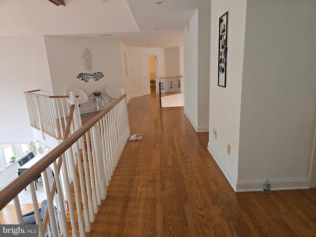 hallway with wood finished floors, an upstairs landing, and baseboards