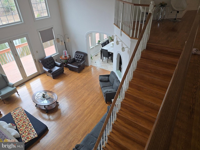 living room featuring a towering ceiling, visible vents, wood finished floors, and stairs