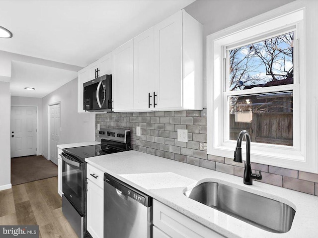 kitchen featuring white cabinets, stainless steel appliances, a sink, and wood finished floors