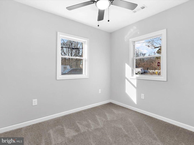 carpeted empty room with baseboards, visible vents, and ceiling fan