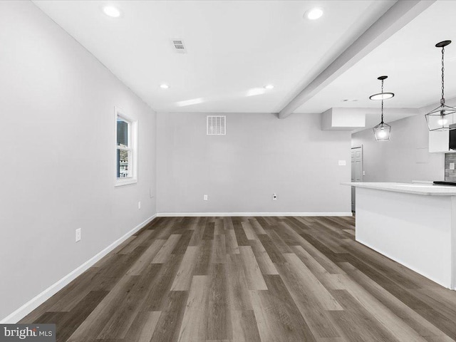 unfurnished living room with visible vents, baseboards, dark wood-style flooring, beam ceiling, and recessed lighting