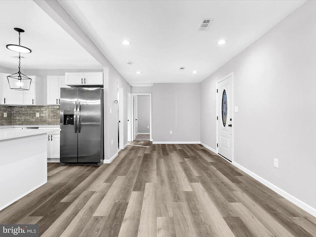 kitchen featuring light countertops, decorative backsplash, white cabinetry, wood finished floors, and stainless steel fridge with ice dispenser