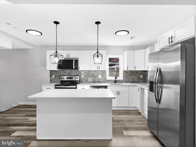 kitchen featuring wood finished floors, appliances with stainless steel finishes, a kitchen island, and a sink