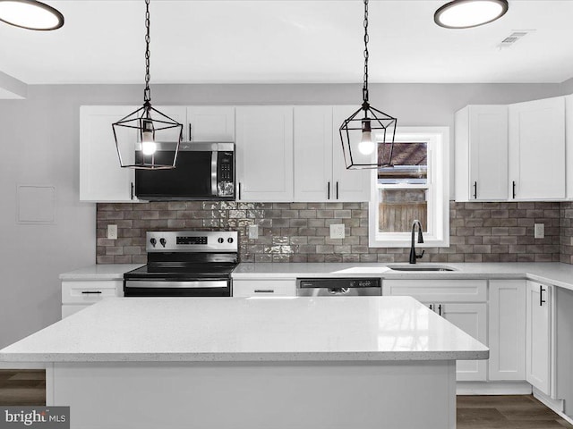 kitchen with appliances with stainless steel finishes, white cabinetry, a sink, and tasteful backsplash