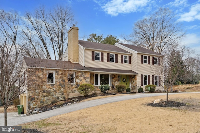 view of front facade featuring stone siding and a chimney