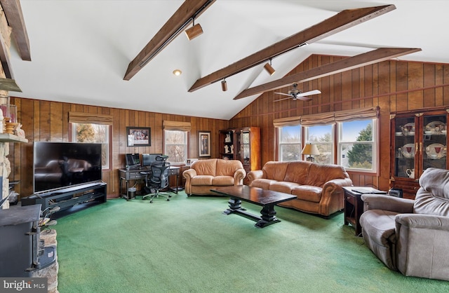 living room featuring vaulted ceiling with beams, carpet floors, wood walls, a ceiling fan, and track lighting