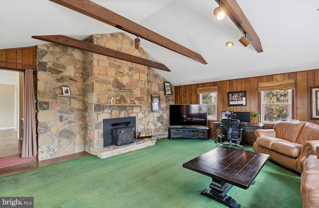 carpeted living area featuring vaulted ceiling with beams, wood walls, and a wood stove