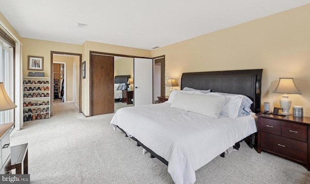 bedroom with a closet, light colored carpet, and visible vents