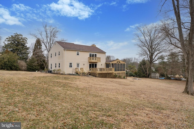 rear view of property featuring a chimney, a yard, a balcony, and a wooden deck