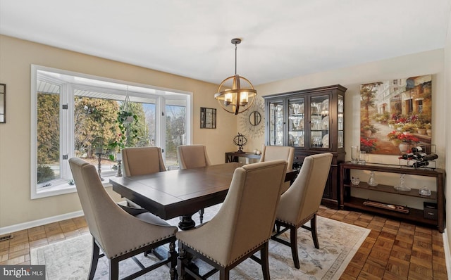 dining room with a chandelier, visible vents, and baseboards