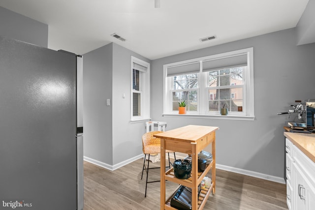 dining area with light wood-style floors, baseboards, and visible vents