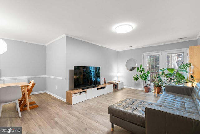 living room with crown molding, light wood finished floors, visible vents, and baseboards