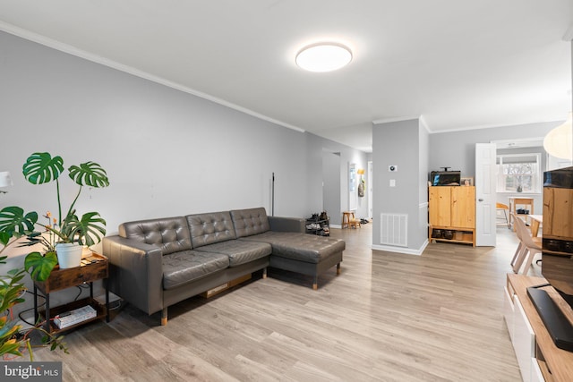 living room featuring baseboards, ornamental molding, visible vents, and light wood-style floors