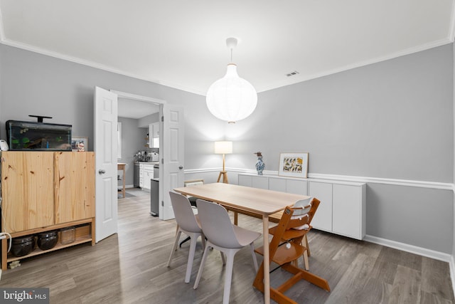 dining space featuring crown molding, visible vents, and wood finished floors