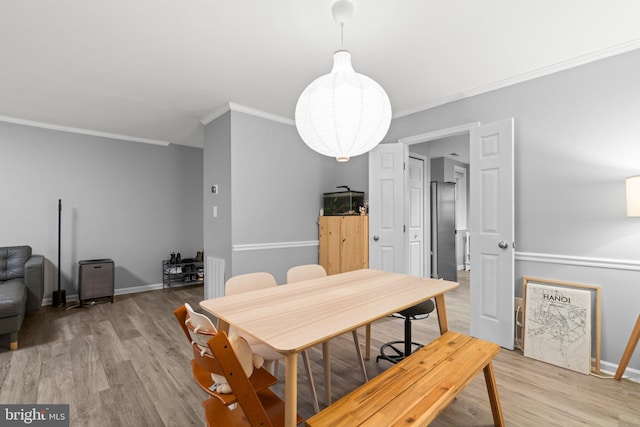 dining area with light wood finished floors, baseboards, and crown molding