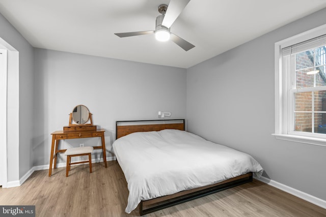 bedroom with light wood finished floors, a ceiling fan, and baseboards