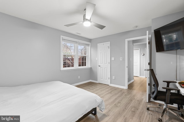 bedroom with a ceiling fan, visible vents, baseboards, and wood finished floors