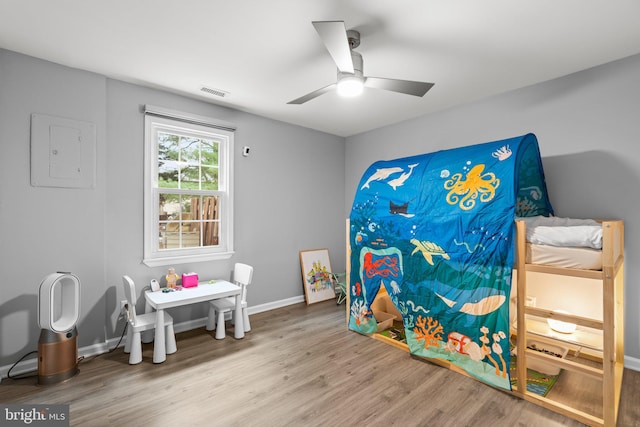 rec room featuring visible vents, a ceiling fan, wood finished floors, electric panel, and baseboards