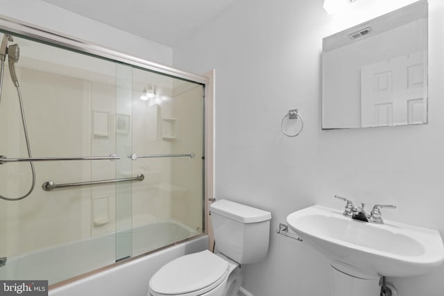 bathroom featuring visible vents, a sink, toilet, and combined bath / shower with glass door