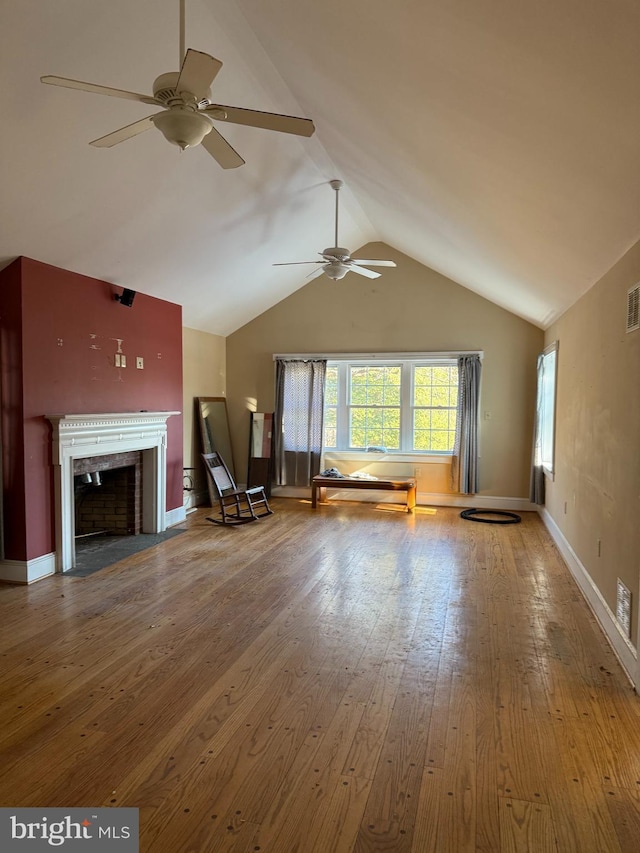 unfurnished living room featuring wood-type flooring, visible vents, a fireplace with flush hearth, vaulted ceiling, and baseboards