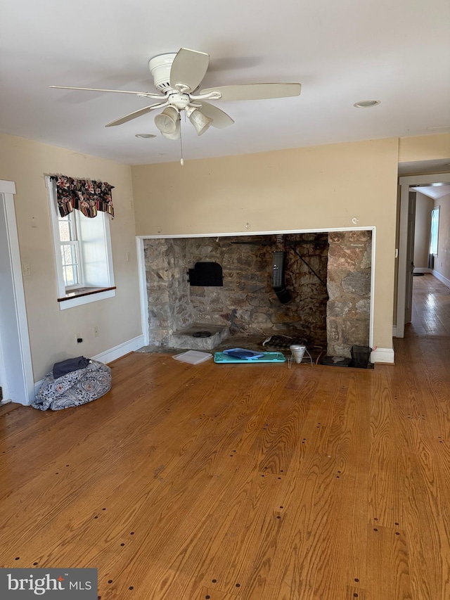 unfurnished living room featuring ceiling fan, baseboards, and wood finished floors