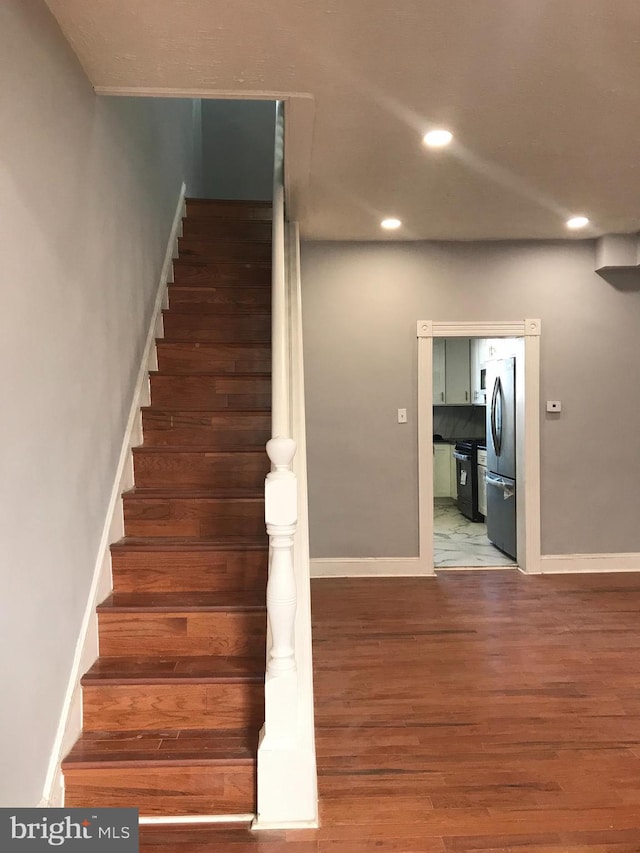 staircase featuring recessed lighting, baseboards, and wood finished floors