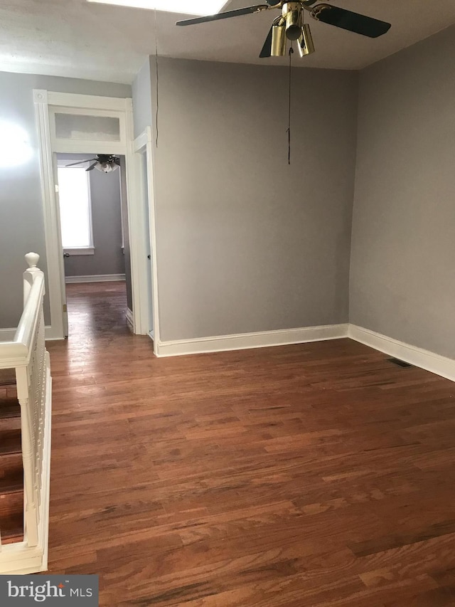 empty room with a ceiling fan, baseboards, and wood finished floors