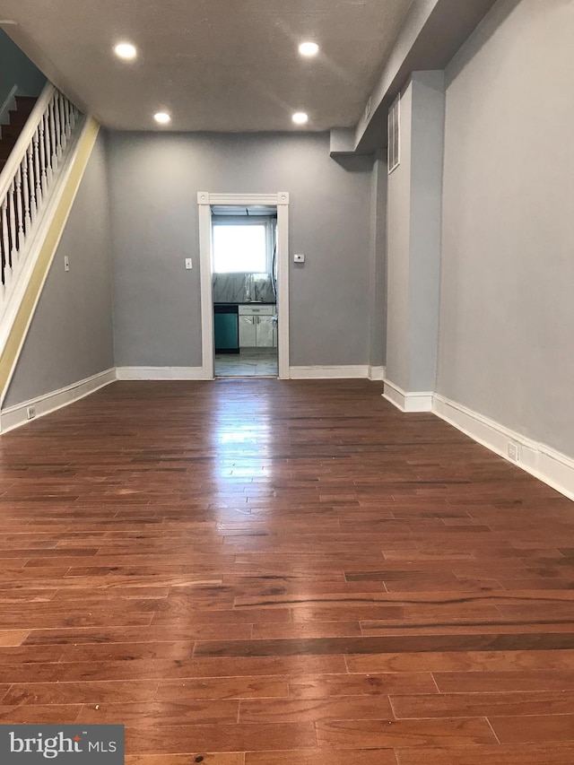 spare room featuring stairs, baseboards, wood finished floors, and recessed lighting