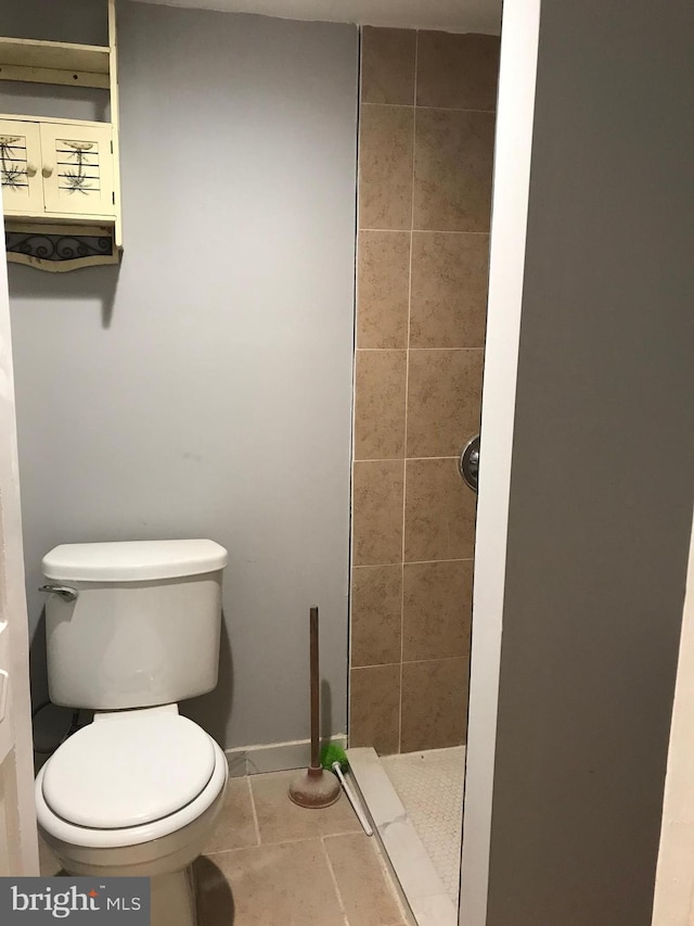 full bath featuring tiled shower, tile patterned flooring, and toilet