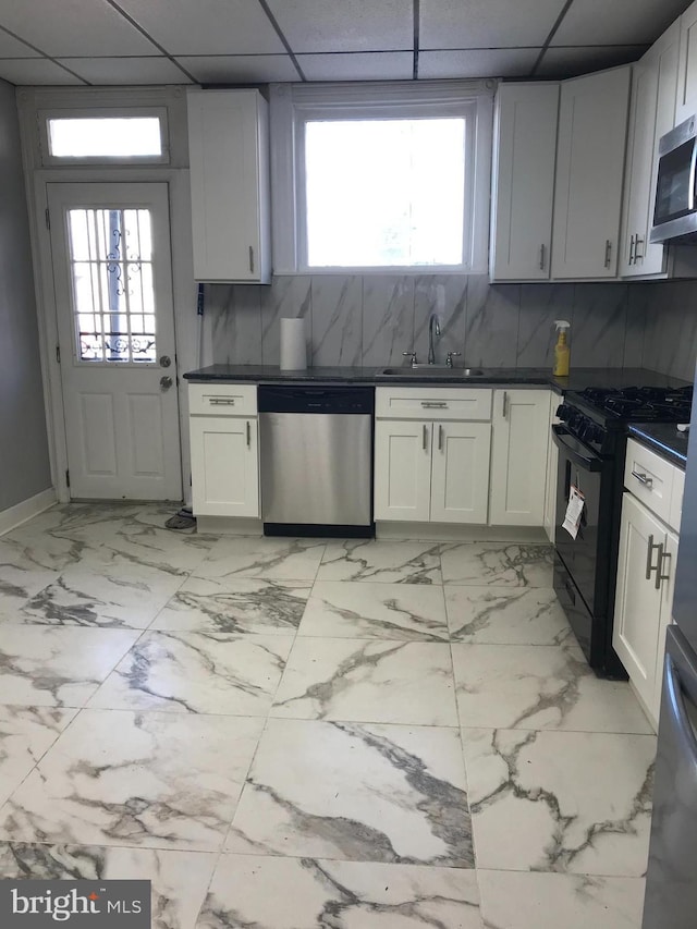 kitchen featuring appliances with stainless steel finishes, a drop ceiling, a sink, and tasteful backsplash