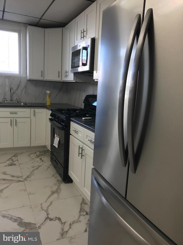 kitchen featuring a sink, marble finish floor, appliances with stainless steel finishes, decorative backsplash, and dark countertops