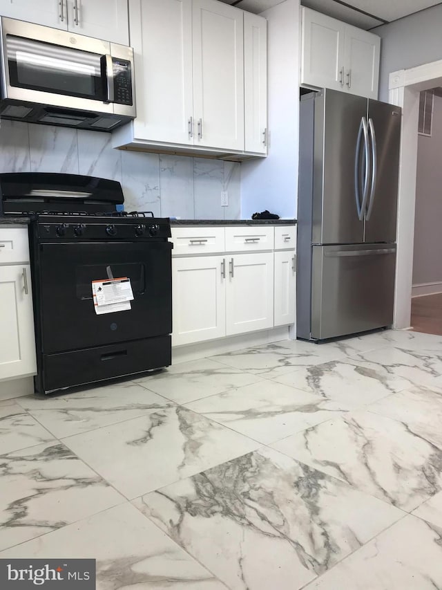 kitchen with dark countertops, white cabinetry, appliances with stainless steel finishes, and backsplash