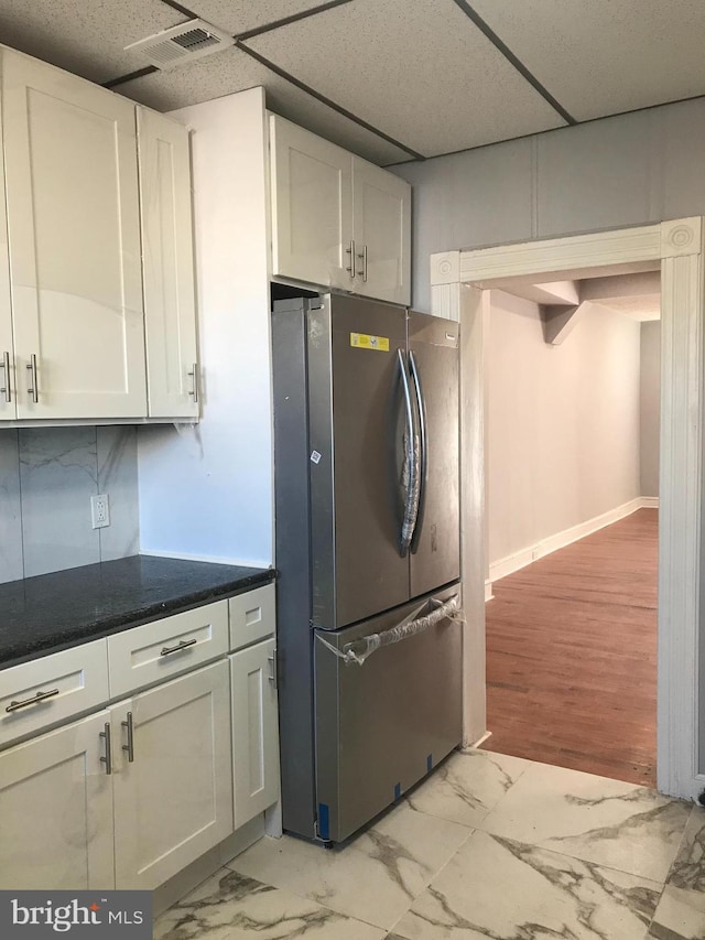 kitchen featuring a paneled ceiling, visible vents, white cabinetry, marble finish floor, and freestanding refrigerator