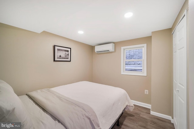 bedroom featuring baseboards, a wall mounted AC, wood finished floors, and recessed lighting