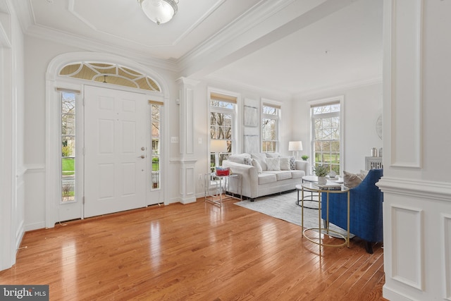 foyer entrance with light wood-style flooring, ornate columns, and a wealth of natural light