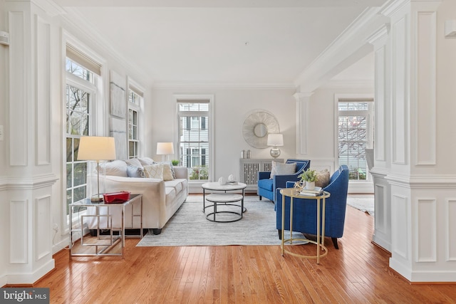 interior space featuring a decorative wall, ornate columns, hardwood / wood-style floors, and ornamental molding