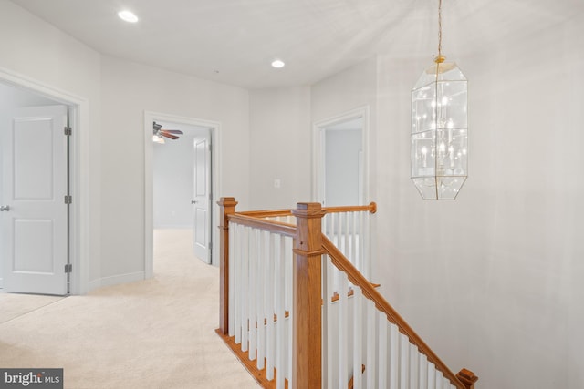 corridor with baseboards, a notable chandelier, an upstairs landing, recessed lighting, and light carpet