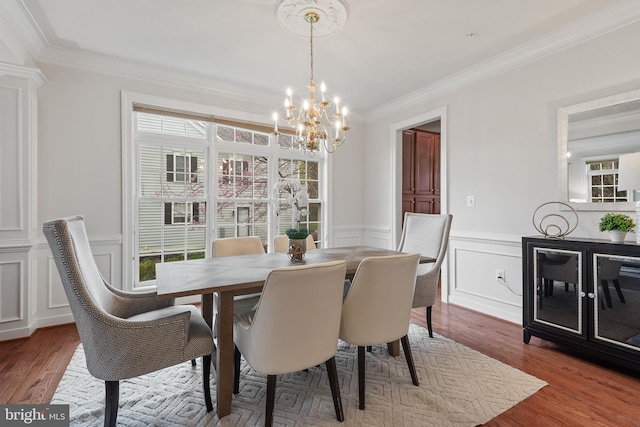 dining area with a decorative wall, a notable chandelier, and ornamental molding