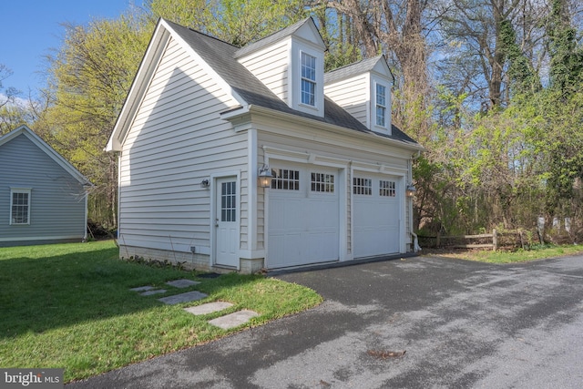 exterior space with a garage, a yard, roof with shingles, and driveway