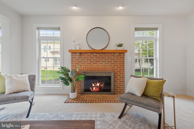 sitting room with carpet, a brick fireplace, and baseboards