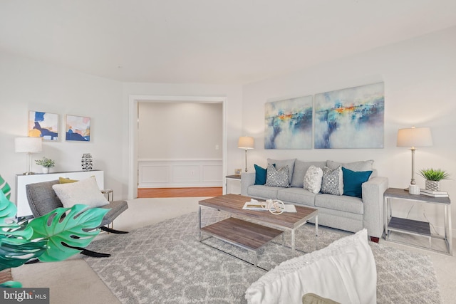 living room featuring a decorative wall and a wainscoted wall