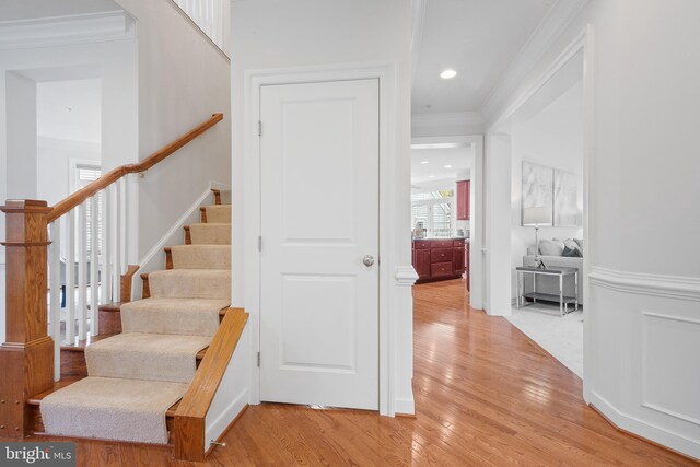 stairs featuring ornamental molding and wood finished floors