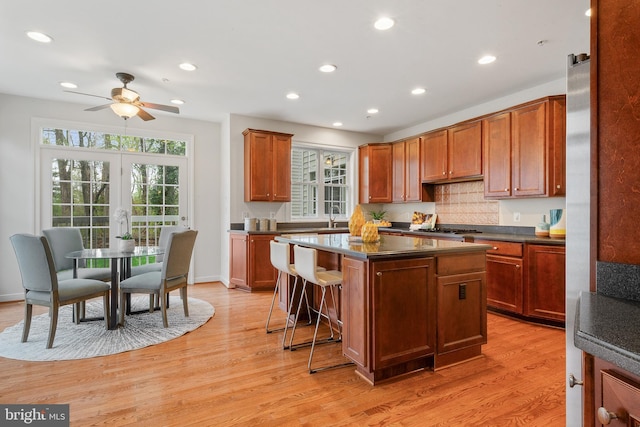 kitchen with dark countertops, a center island, a ceiling fan, and a healthy amount of sunlight