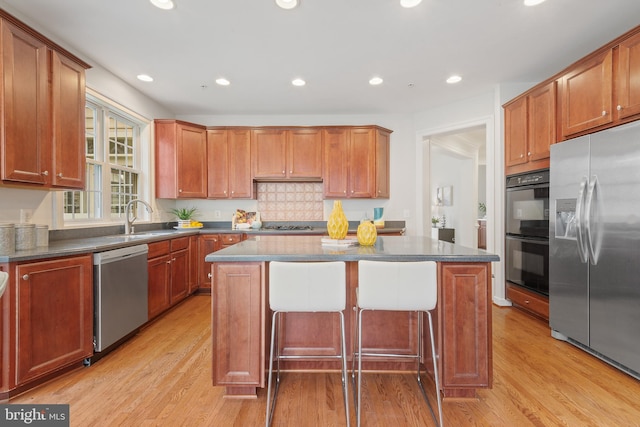 kitchen with a center island, light wood-type flooring, a sink, and appliances with stainless steel finishes
