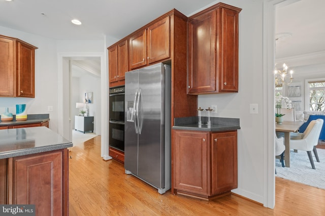 kitchen featuring dobule oven black, light wood-style floors, stainless steel fridge with ice dispenser, and dark countertops