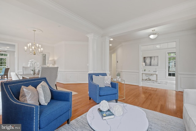 living room featuring ornamental molding, wainscoting, a notable chandelier, and wood finished floors