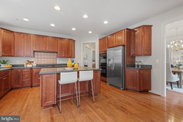 kitchen featuring light wood finished floors, stovetop, dark countertops, and stainless steel refrigerator with ice dispenser