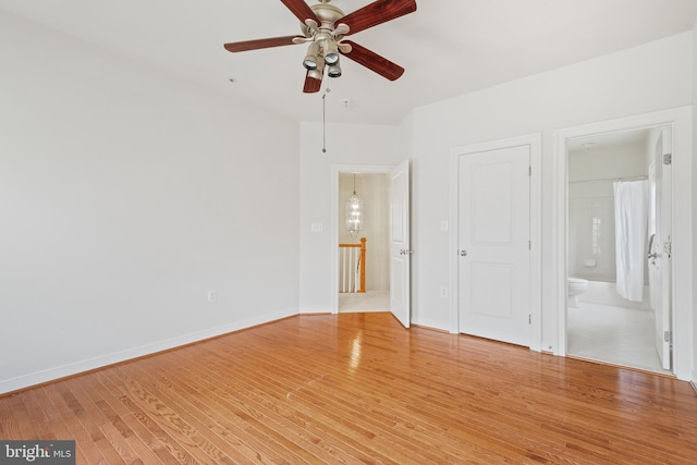 unfurnished bedroom featuring light wood finished floors, baseboards, and connected bathroom