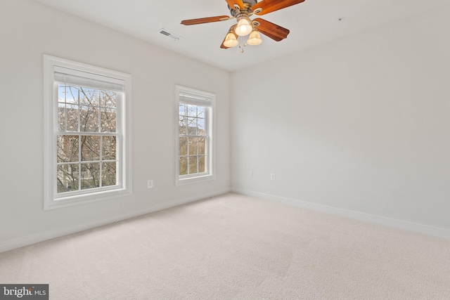 carpeted empty room with visible vents, baseboards, and ceiling fan